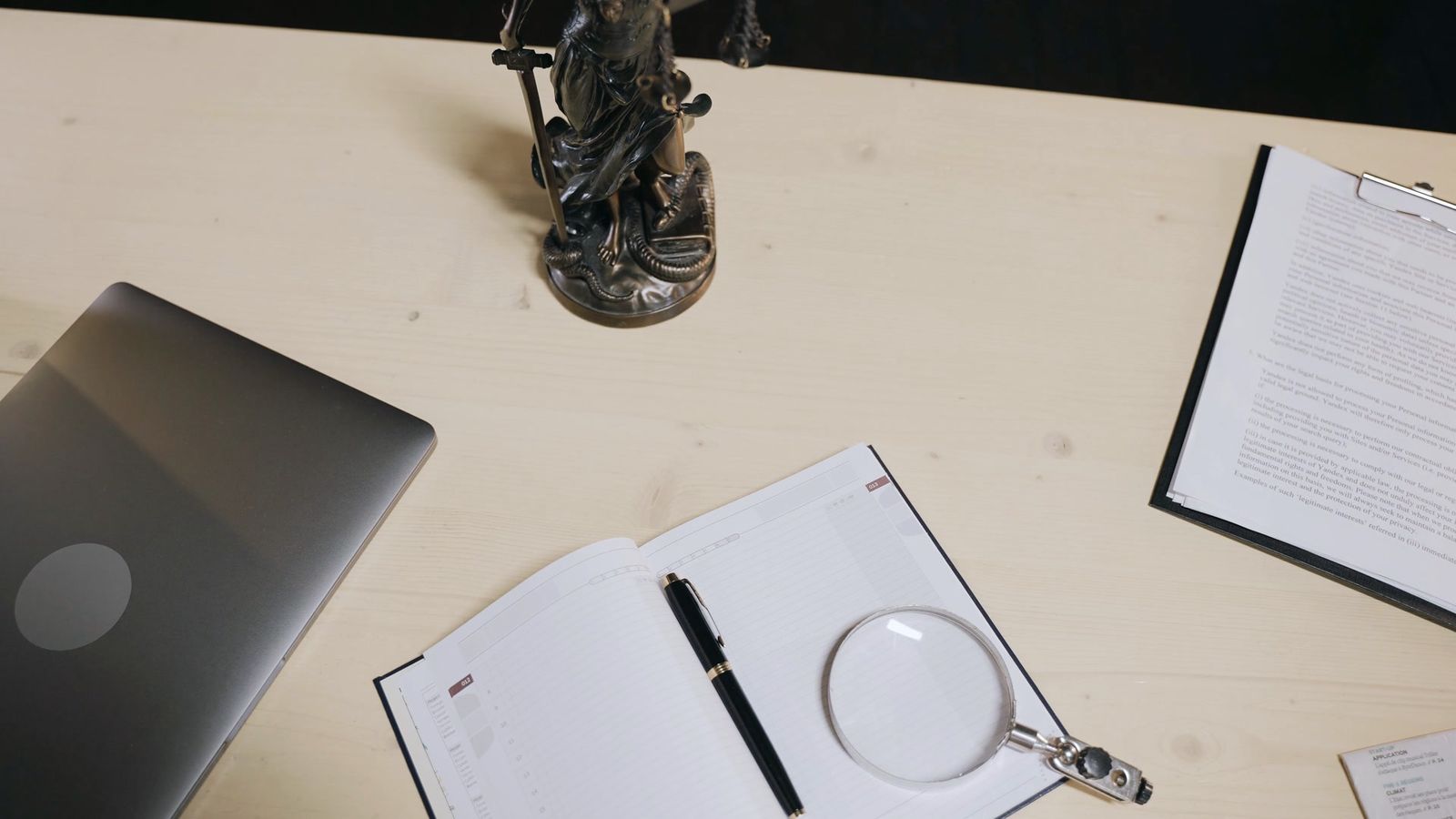 An open diary, pen and magnifying glass on a desk