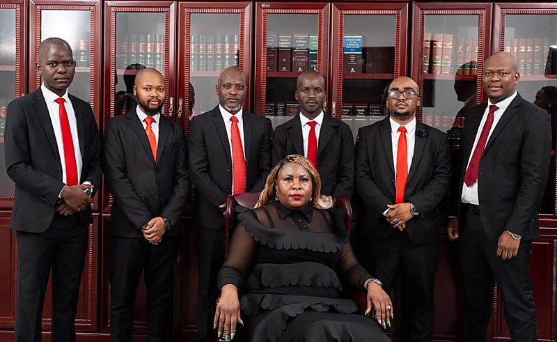 Attorneys and staff of Ngomana & Associates in front of mahogany law-book cabinets