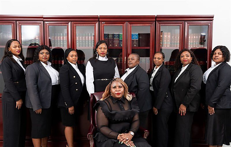 Attorneys and staff of Ngomana & Associates in front of mahogany law-book cabinets
